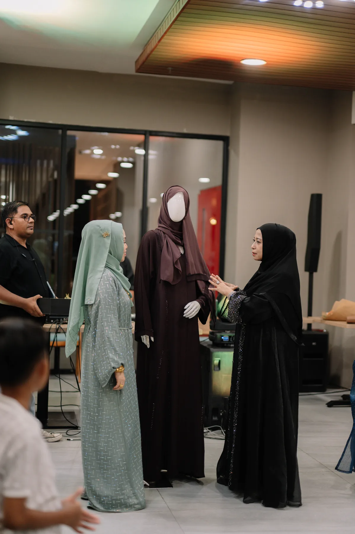 Presentasi busana Heelwa di samping manekin dengan pengunjung menyaksikan