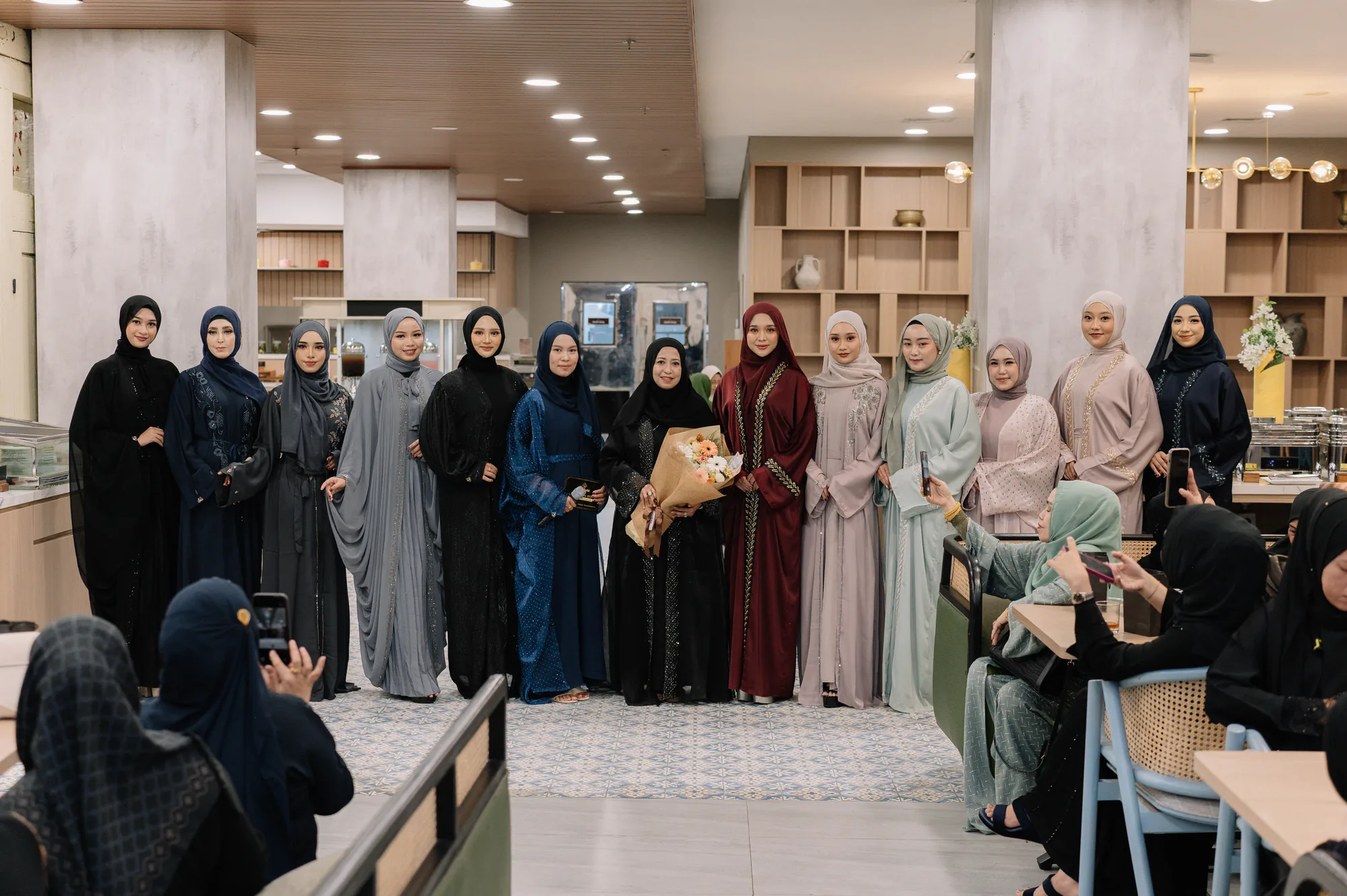 Para model berfoto bersama dalam busana Heelwa di MYZE Hotel Sumenep, dengan pengunjung di sekitar area acara